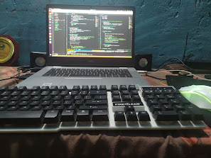 Laptop with code editor open beside keyboard and speakers